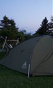 Green tent, with bike in the background at dusk. Stevns Klint